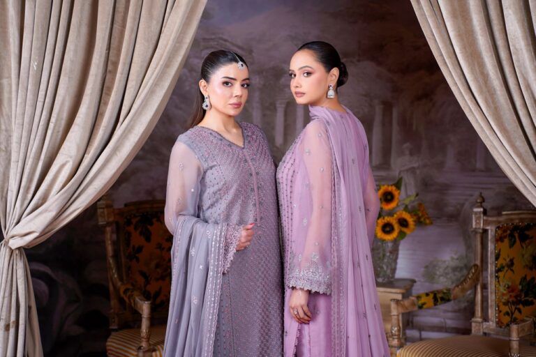 Fashion portrait of two women in elegant traditional Eastern dresses with floral backdrop.