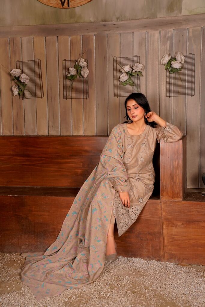 Fashionable woman in embroidered Eastern attire seated elegantly indoors.