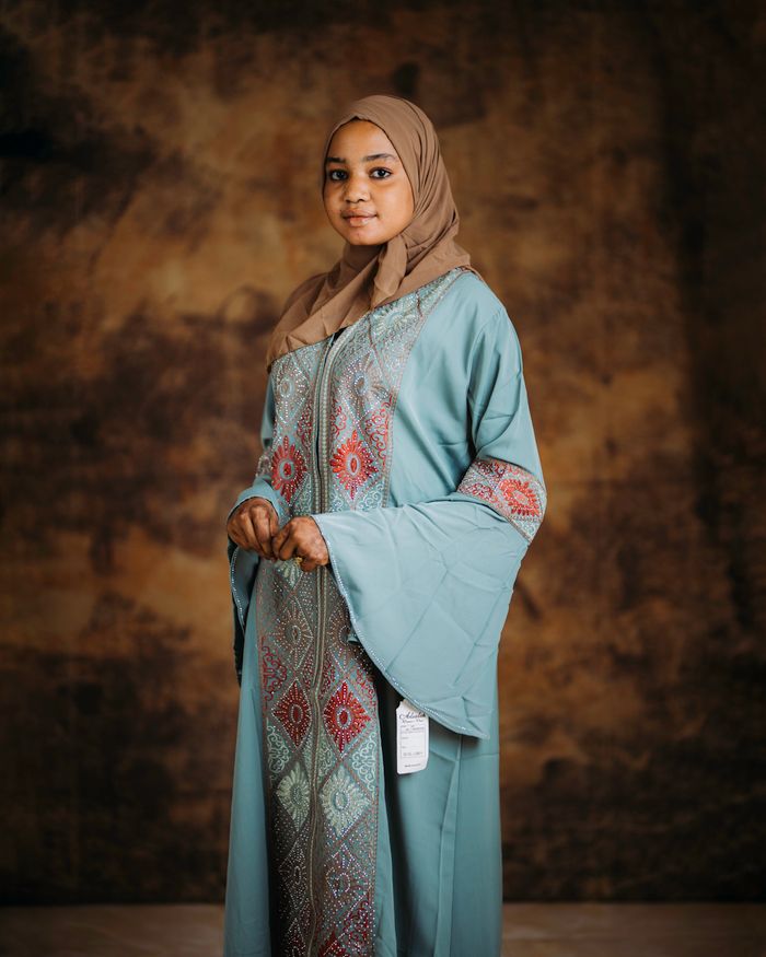 A graceful woman in a traditional robe with intricate patterns, posing in a studio.
