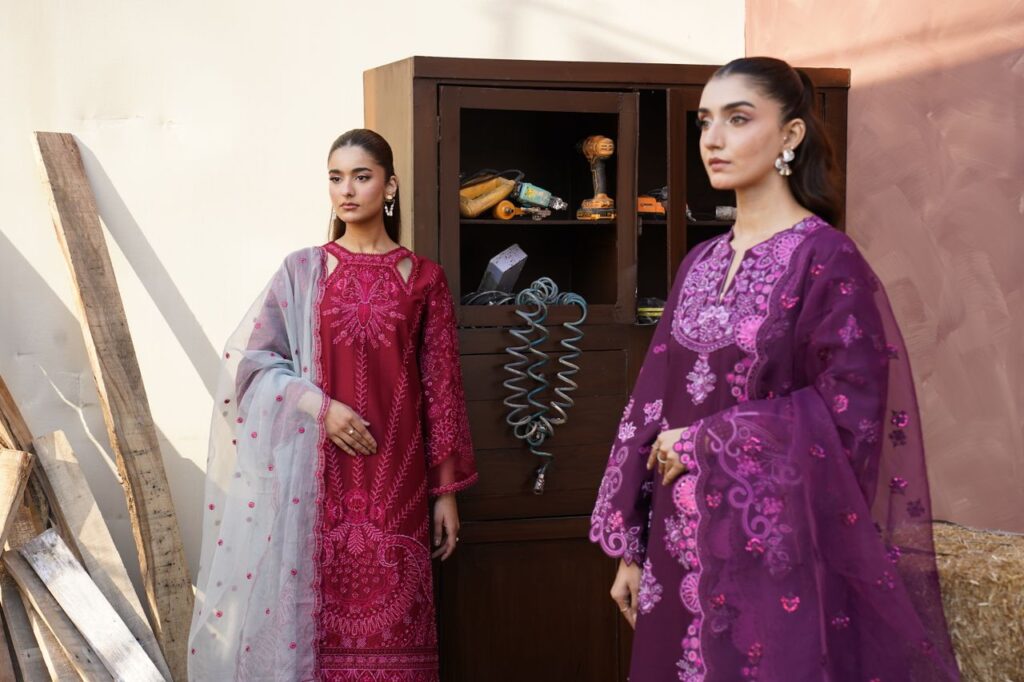 Two women pose elegantly in colorful traditional dresses, adding vibrancy to a rustic background.