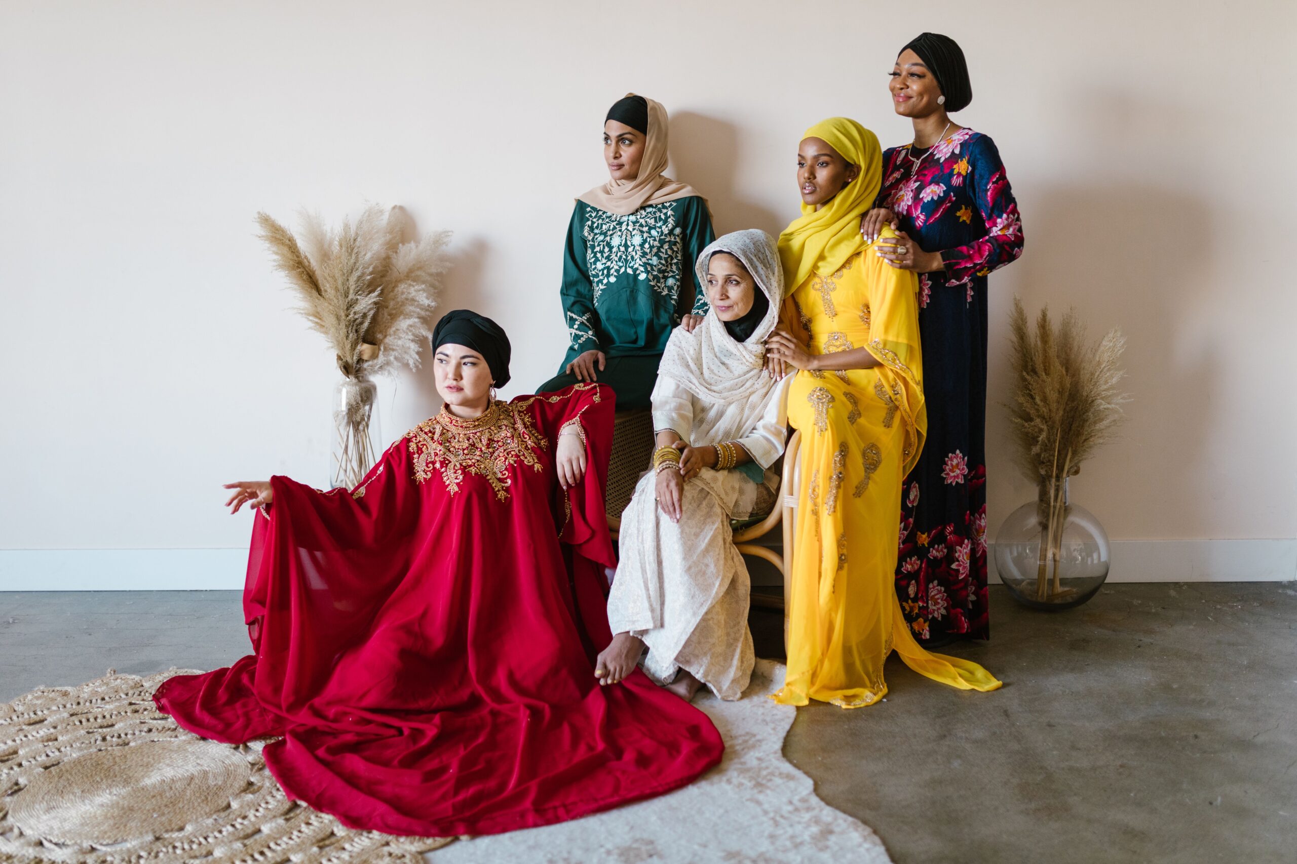 A diverse group of women in colorful traditional dresses posing indoors, showcasing cultural richness.