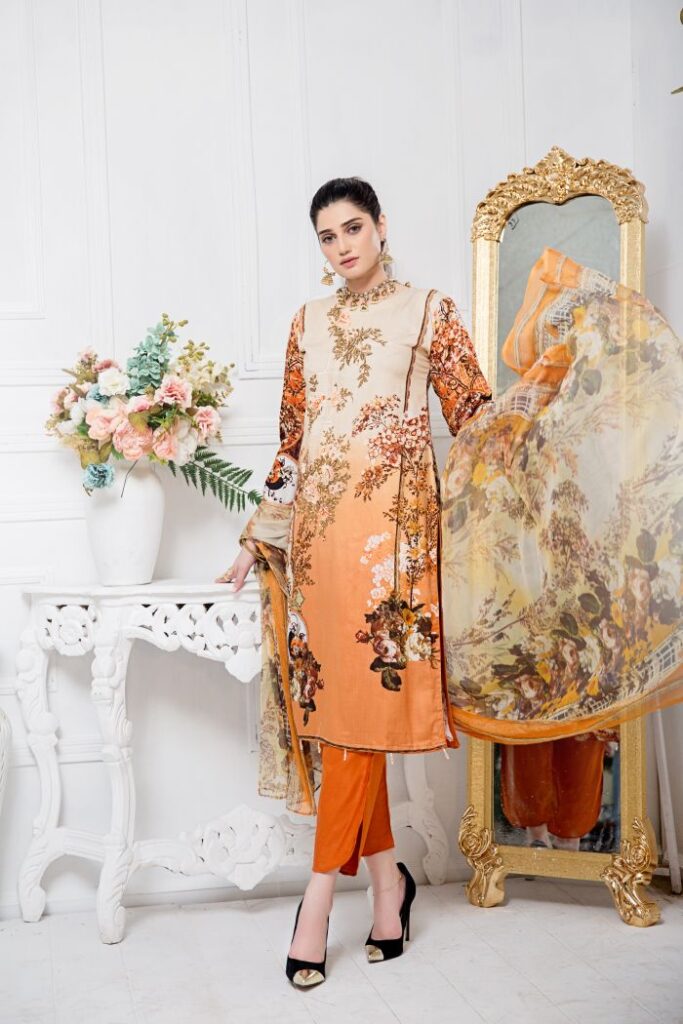 Indian woman posing in traditional orange floral dress with dupatta indoors.
